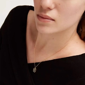 Elegant gold necklace featuring a letter E pendant with colorful zircon stones on a model