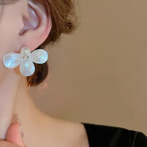 Elegant flower stud earrings with white pearl and mother of pearl petals on a model