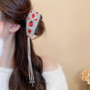 Detail of grey flocked hair clip with red teardrop crystals and long rhinestone tassels