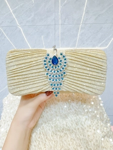 Close-up of gold clutch bag with peacock blue crystal and water-drop gemstone detail