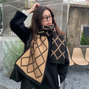 Detail of classic black and brown checkered knit scarf on a model in outdoor street setting
