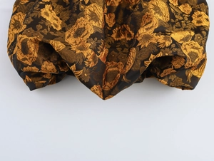 Dettaglio di tessuto jacquard pregiato con motivi floreali dorati su sfondo scuro