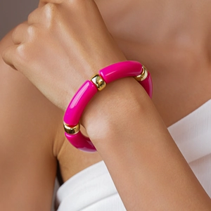 Primo piano di perle in acrilico rosa e distanziatori dorati su un elegante bracciale