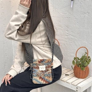 Close-up of plush knit mini crossbody bag with adjustable rope strap and brand label