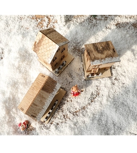 Top view of wooden Christmas house ornaments on faux snow with festive miniature figures