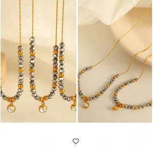 Close-up of beaded necklace featuring grey faceted crystals and zircon pendant on a ceramic dish