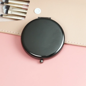 Overhead view of a sleek black portable folding makeup mirror with a pink brush pouch