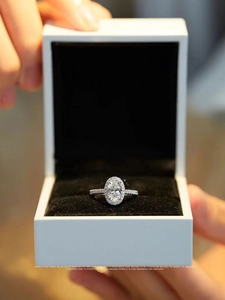 Macro detail of oval cut halo diamond ring in velvet gift box with pavé band stones