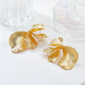 Detailed view of gold leaf earrings with textured metallic petals on a white tray
