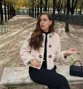 Détail de la veste en polaire beige avec boucles métalliques dans un décor d'automne