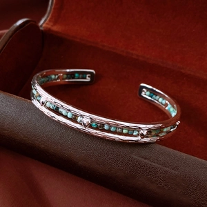 Macro shot of silver metal bangle with turquoise beads and heart charms on leather background