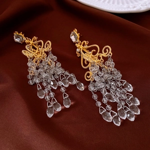 Detailed view of vintage gold tassel earrings with crystal beads on dark red velvet