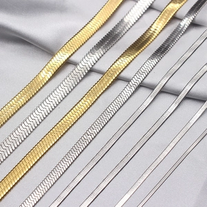 Golden and silver flat snake bone chains in various widths on grey silk background