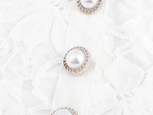 Gros plan sur la dentelle blanche et le bouton perle vintage avec bordure tressée