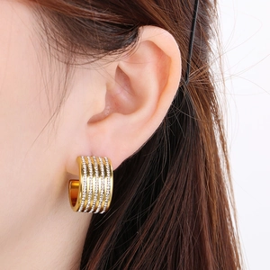 Close-up of golden C-shaped titanium earrings with five rows of sparkling white crystals