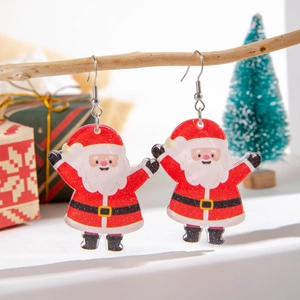 Close-up of Santa Claus resin earrings with glitter hanging on a branch in holiday setting