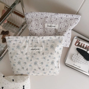 Detail view of small floral cotton makeup bags with simple wish labels on a clean desk