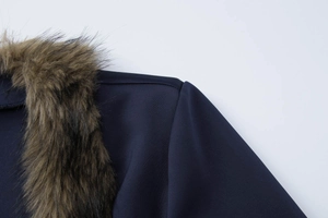 Close-up of the shoulder seam and fluffy brown faux fur collar on dark blue coat