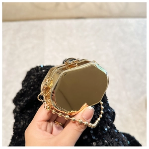 Detail of octagonal gold mirror evening bag with decorative beaded chain and metal hinge