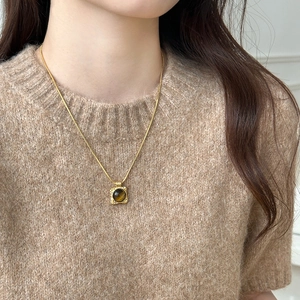 Close-up of a vintage 18K gold plated tiger eye pendant necklace on a model