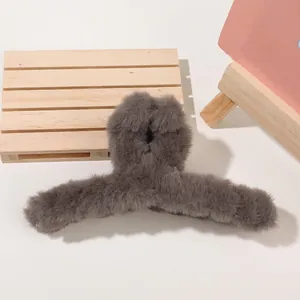 Detail of dark grey plush shark clip on wooden tray showing soft faux fur texture