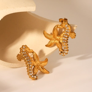 Vue macro de boucles d'oreilles hippocampe et étoile de mer dorées avec strass blancs
