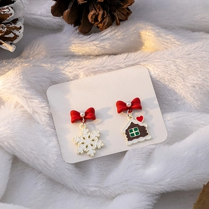 Detailed view of asymmetric Christmas earrings with snowflake and gingerbread house charms