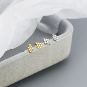 Detailed close-up of four minimalist geometric beaded stud earrings in gold and silver