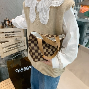 Detail of checkered corduroy tote bag showing textured brown fabric and sturdy handles