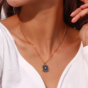 Detail view of a gold square shell pendant necklace with a starburst on model's neck