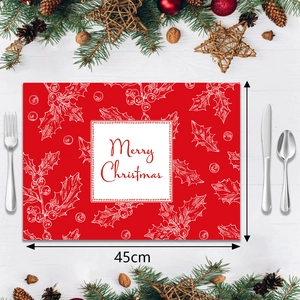 Close-up of a red Christmas placemat featuring white holly prints and a Merry Christmas text