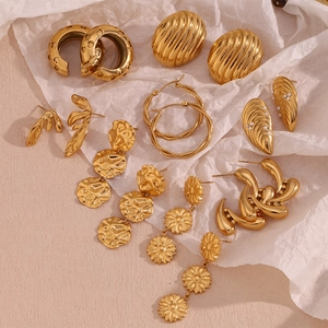 Selection of 18K gold plated earrings with textured hoops and heart shapes on beige fabric