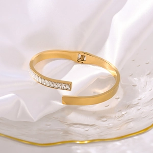 Goldenes Edelstahl-Scharnierarmband mit rechteckigem Zirkonia auf Seidenhintergrund