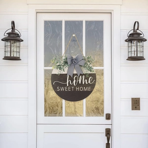 Detail of wooden home sweet home sign with striped bow and eucalyptus on white door