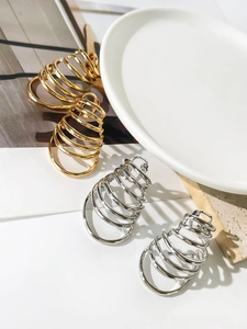 Detail of layered spiral hoop earrings in gold and silver finishes on elegant props
