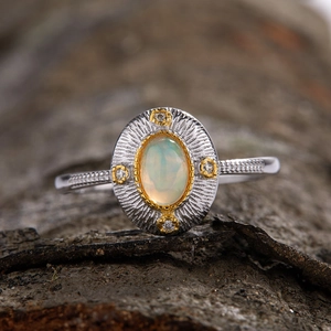 Macro shot of an oval opal ring with gold and silver bands on natural bark background