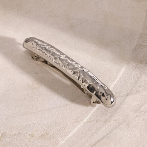 Macro shot of silver hammer texture hair clip with metal spring on stone background