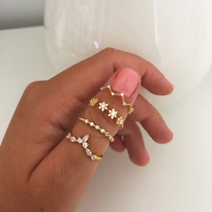 Detailed view of four-piece gold ring set featuring snowflake and V-shape zircon designs