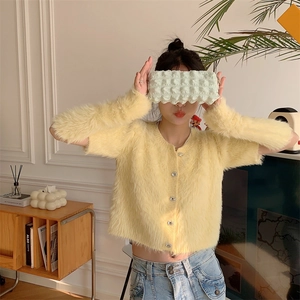 Detail of soft yellow faux mink fur cardigan texture with luxury diamond buttons