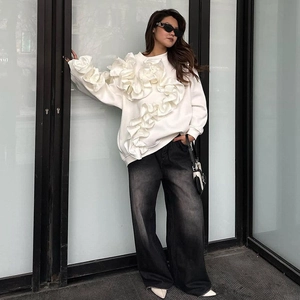 Photo de rue d'un sweat blanc à volants porté avec un jean noir à jambes larges