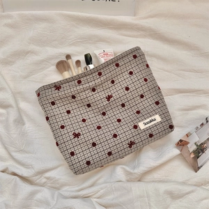 Detail of red polka dot and gingham cosmetic bag showing spacious interior storage