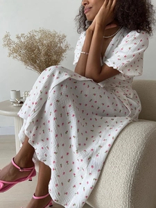 Close-up of pink floral print and tie-waist detail on white cotton summer dress