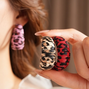 Close-up of pink, beige and red leopard print C-shaped earrings with leather texture