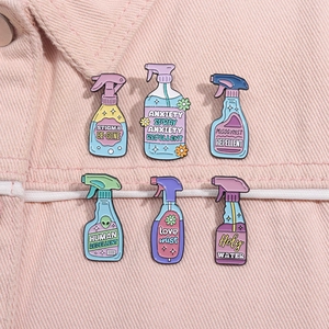 Macro shot of colorful enamel spray bottle pins on pink denim fabric background