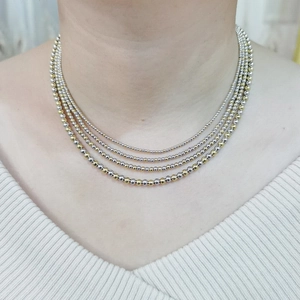 Detail of four-layer gold and silver beaded necklace on model with ribbed white top