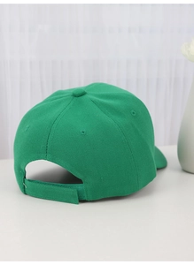 Rear view of green baseball cap showing adjustable strap and fabric texture on white table