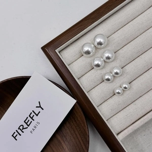 Macro shot of four pairs of graduated white pearls on a beige velvet jewelry tray