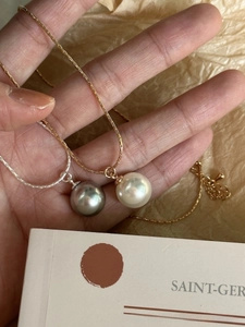 Detail showing silver and gold snake chains with gray and white pearls held by hand