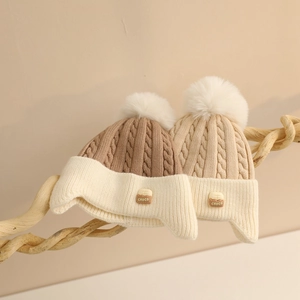 Detailed cable knit pattern on baby winter hats with fluffy pom poms and choc label