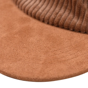 Macro shot of brown corduroy fabric texture and striped rubber detail on baseball cap